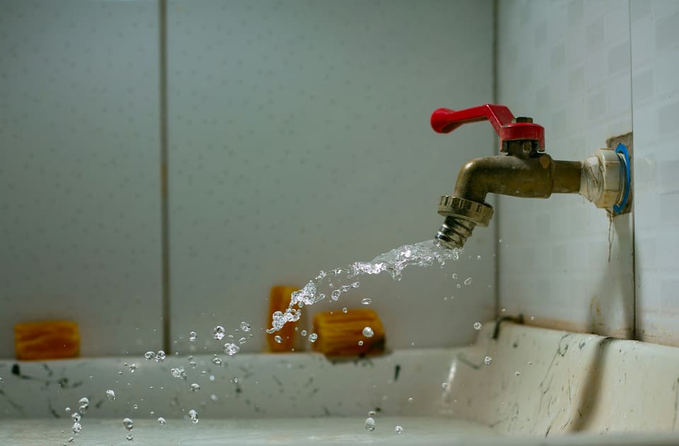 Water running from a brass tap into a utility sink